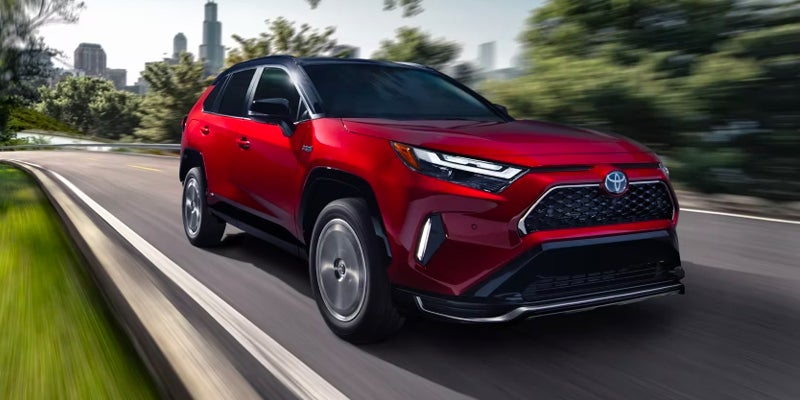 Red 2024 Toyota RAV4 Prime Frederick, MD Driving with City View in Back