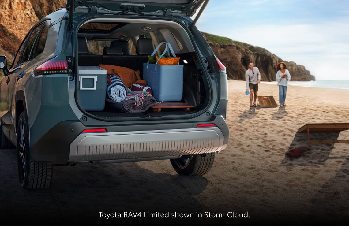 Rear three-quarter view of a 2026 Toyota RAV4 Limited in Storm Cloud with the liftgate open, displaying a fully loaded cargo area.