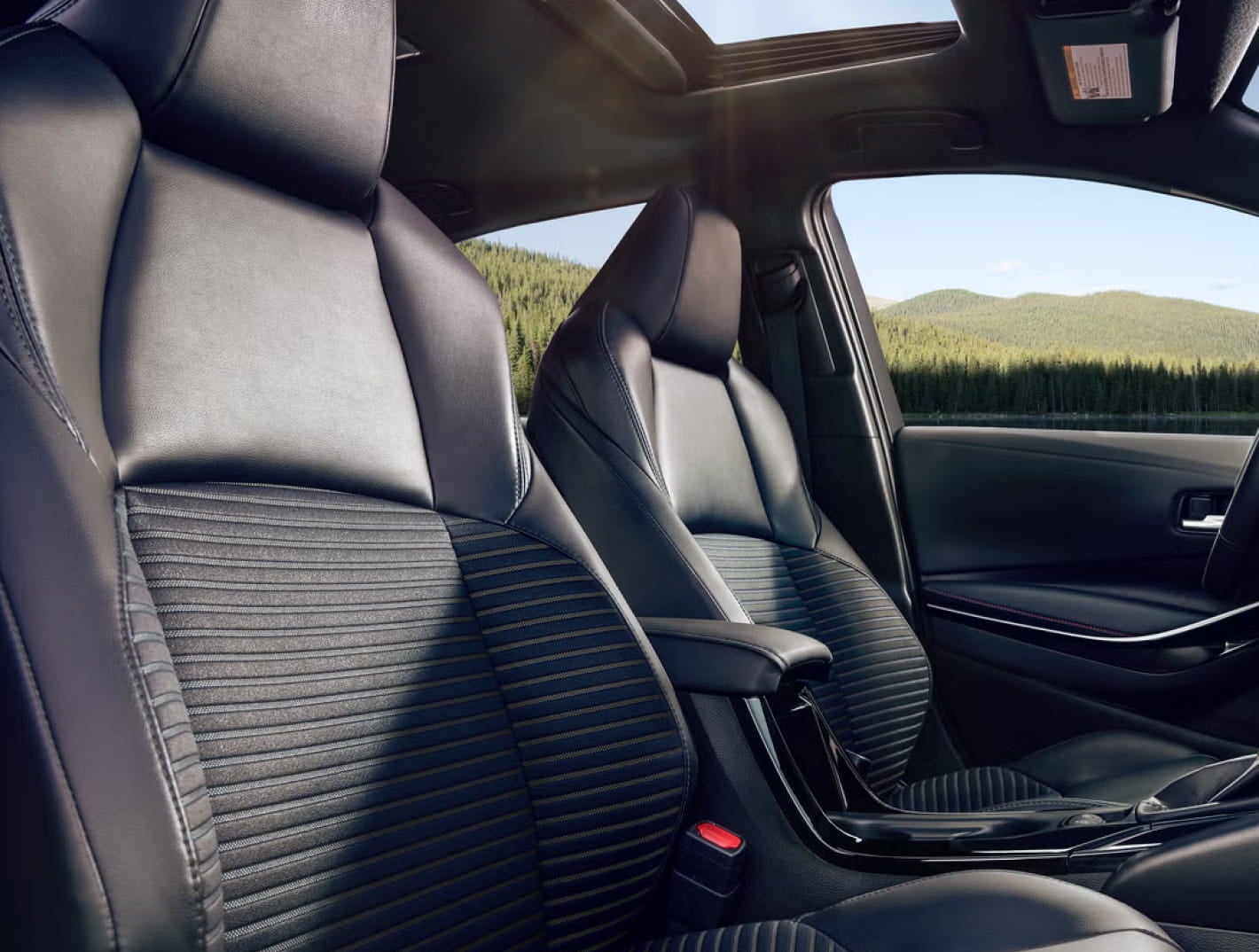 Black front seats and sunroof inside a Toyota Corolla.