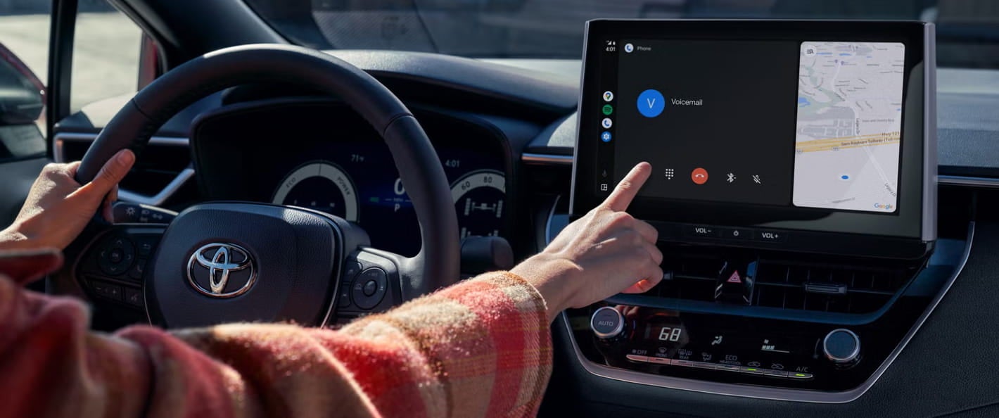 Driver using the touchscreen display inside a Toyota Corolla.